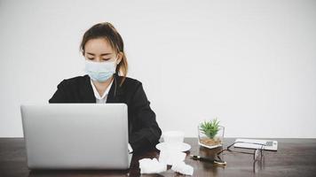 sjuk ung asiatisk affärskvinna som bär skyddande ansiktsmask foto