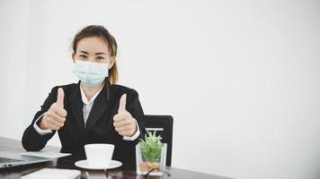 kvinnlig kontorsarbetare i mask visar tummen upp foto