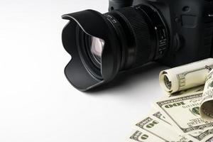 en svart digitalkamera på sedlar med vit bakgrund. foto