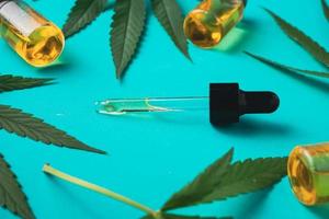 cannabisolja i droppflaskor med gröna blad på grön bakgrund. alternativ medicin koncept. foto