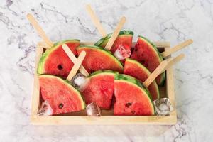 vattenmelonskivor på pinnar med isbitar. färska vattenmelon popsicles i träskål. foto