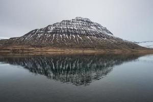 reflektionen av holmatindur berget av eskifjordur staden östra island. foto