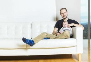far med baby i soffan som tar sig god tid foto