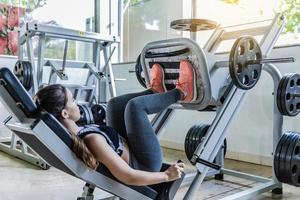 söt ung kvinna under ett benpass i ett gym foto