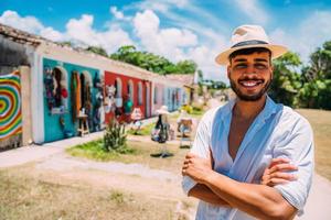 turist gör selfie i porto seguros historiska centrum. latinamerikansk man i hatt och armarna i kors ler mot kameran foto