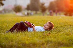 bedårande pojke med gitarr, sitter på gräset