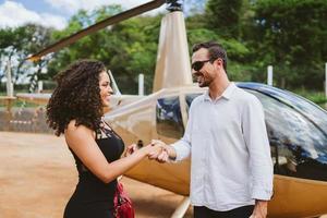 framgångsrik smart snygg ung latinsk kvinna nära helikopter med pilot. lyxigt livsstilskoncept foto