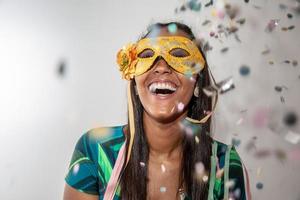 glad ung kvinna med mask och konfetti på karnevalsfest. brasiliansk karneval foto