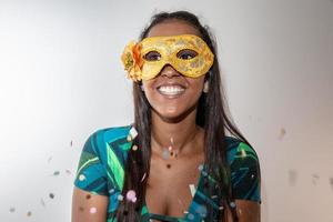 glad ung kvinna med mask och konfetti på karnevalsfest. brasiliansk karneval foto