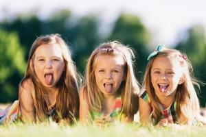 tre små flickor som räcker ut tungan foto