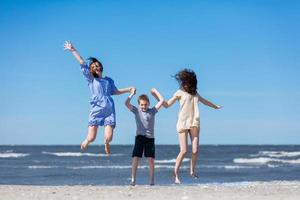 lycklig familj hoppar högt på stranden. foto