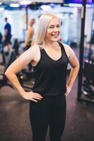 leende kvinna står i ett gym foto