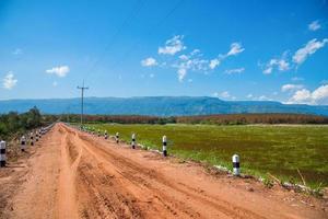grusväg grus i jordbruket landsbygden gå till berget blå himmel bakgrund foto