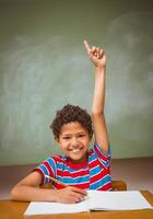 liten pojke som lyfter handen i klassrummet foto