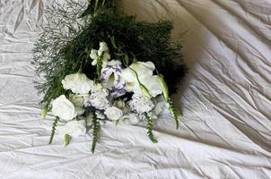 vit bukett blommor på en vit bakgrund, mot bakgrund av sänglinne, en bukett grön färg, bakgrund, vita vackra blommor foto