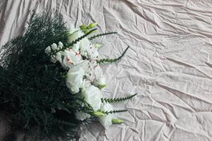 vit bukett blommor på en vit bakgrund, mot bakgrund av sänglinne, en bukett grön färg, bakgrund, vita vackra blommor foto