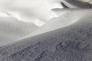 djupa snödrivor fruset vatten snö faller under vintersäsongen. de djupa snödrivorna är upplysta av solen foto