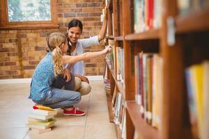 lärare och liten flicka som väljer bok i biblioteket