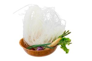 råa risnudlar i en skål på vit bakgrund foto