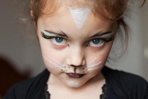 en liten flicka med ansiktet målade som en katt foto