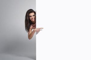 glad kvinna som pekar på kopieringsutrymme på whiteboard foto