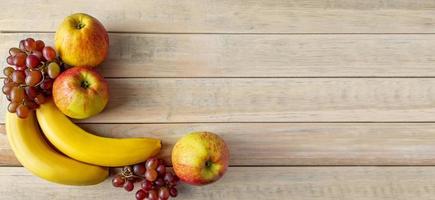 mogna frukter på trä bakgrund. bananer, äpplen och vindruvor. skörd koncept. foto