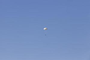 fallskärmshoppare som stiger ner på den blå himlen foto
