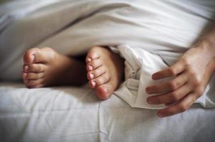 sovande barnfötter och hand på vitt sänglinne