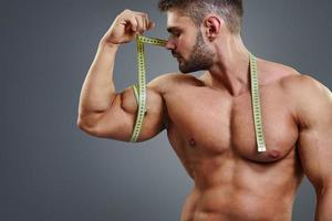 kroppsbyggare som mäter biceps med måttband foto