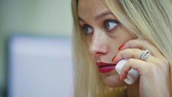 ung blond kvinna på kontoret pratar i telefon framför datorn, extremt nära foto