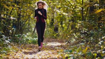 ung löpare flicka har jogging på hösten väg täckt med fallna löv. sport hälsosam livsstil koncept foto