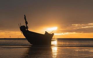 siluett fiskare på båten på stranden. foto