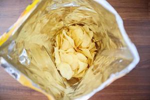 potatischips i öppen snackspåse närbild på bordsgolvet foto