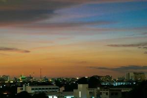 ger en varm känsla, solnedgång bakom stadsbyggnaden, siluett stadens höga byggnader, byggnadssilhuett igen vacker himmelbakgrund och frihetskoncept. foto