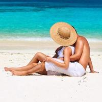 par i vitt kopplar av på en strand vid Maldiverna