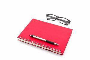 röd dagbok med gamla glasögon och penna.