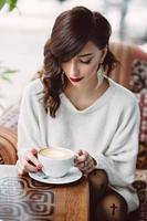 ung flicka som dricker kaffe i ett trendigt kafé foto