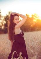 vacker flicka i vetefält vid solnedgången
