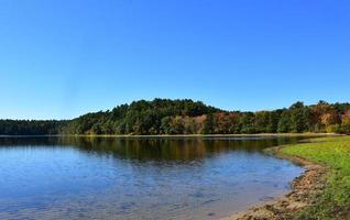 höstlövverk på träd som omger en sjö i new england foto