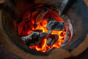 orange låga av träkol i grillen gjord av gammal lera. mjukt fokus. foto