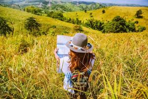 asiatiska kvinnor reser koppla av i semestern. stå naturlig touch berget fält sommar. visa karta resor utforska. i Thailand foto