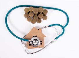 kolla upp hus och investeringskoncept. stetoskop med miniatyrhus och pengar foto
