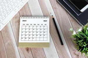 vit maj 2023 kalender på trä skrivbord med kontorspapper. foto