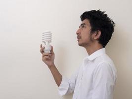 man som håller energibesparande glödlampa för lampa foto