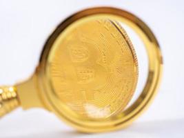 gyllene bitcoin förstoringsglas på en suddig bakgrund av mynt foto