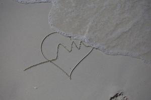 hjärtan ritade på sanden på en strand foto