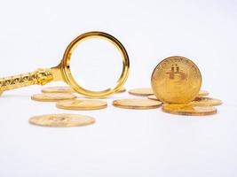 gyllene bitcoin replik och förstoringsglas på vit bakgrund. affärs- och finanskoncept. foto