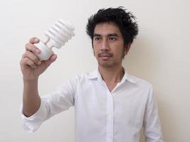 man som håller energibesparande glödlampa för lampa foto