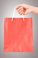 kvinnlig hand som håller röd väska - shopping och semester koncept foto