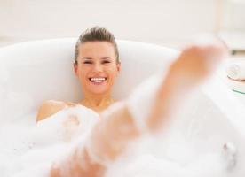 leende ung kvinna som har kul tid i badkaret